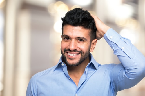 Man has hands on his hair - Is a FUE Hair Transplant Right For You?